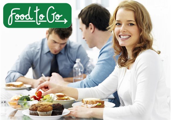 Woman enjoying a light lunch consisting of a salad, turkey sandwich, and muffins.