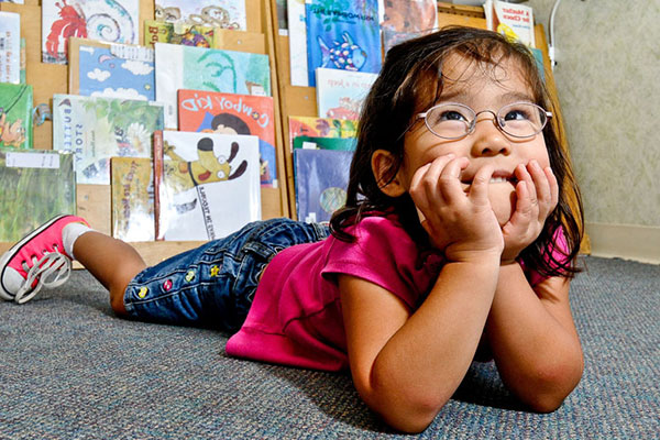 girl laying down in front of a book case