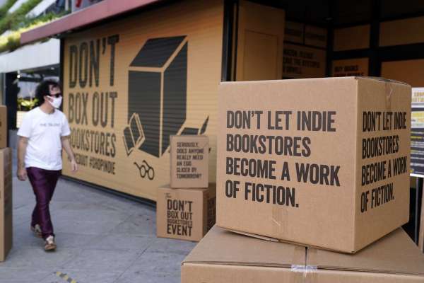 FILE - A pedestrian walks past boxes set up in front of book store Book Soup in West Hollywood, Calif., on Oct. 16, 2020, to encourage shoppers to buy from independent book stores instead of online retailers like Amazon. For independent stores and publishers, the pandemic amplified the divide between the industry's biggest players and everyone else.