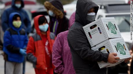 People carry food donated by volunteers from the Baltimore Hunger Project outside of Padonia International Elementary school on December 4, 2020 in Cockeysville, Maryland. 