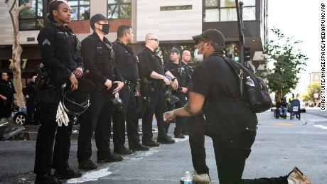 OAKLAND, CA- JUNE 2: A protestor kneels and connects with a female Police Officer near the Oakland Police Department in Oakland, California on June 2, 2020 after the death of George Floyd. Credit: Chris Tuite/ImageSPACE/MediaPunch /IPX