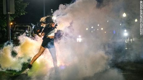 A demonstrator throws back a can of Tear gas on August 25, 2020 in Kenosha, Wisconsin. As the city declared a state of emergency curfew, a third night of civil unrest occurred after the shooting of Jacob Blake, 29, on August 23. Video shot of the incident appears to show Blake shot multiple times in the back by Wisconsin police officers while attempting to enter the drivers side of a vehicle. The 29-year-old Blake was undergoing surgery for a severed spinal cord, shattered vertebrae and severe damage to organs, according to the family attorneys in published accounts.  