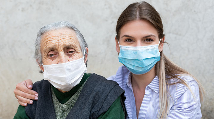 elderly woman and caregiver wearing masks