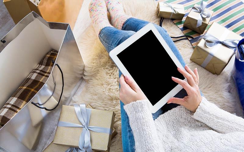 Female shopping online surrounded by holiday gifts