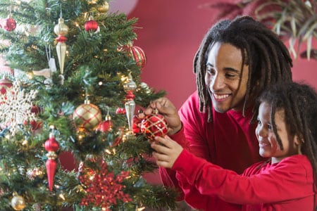 Father and daughter decorating a Christmas tree