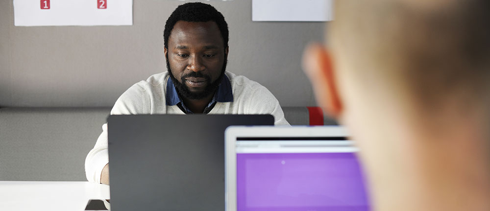 A man using a laptop and taking notes