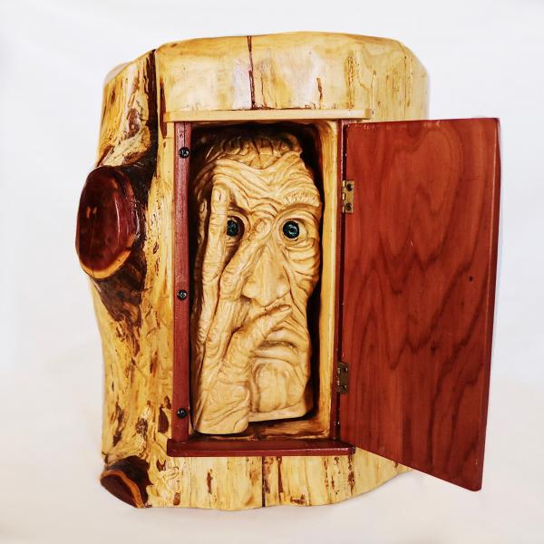 wood carving of a wrinkled face inside a log