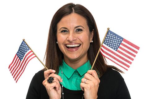 Woman holding an American Flag in each hand and smiling