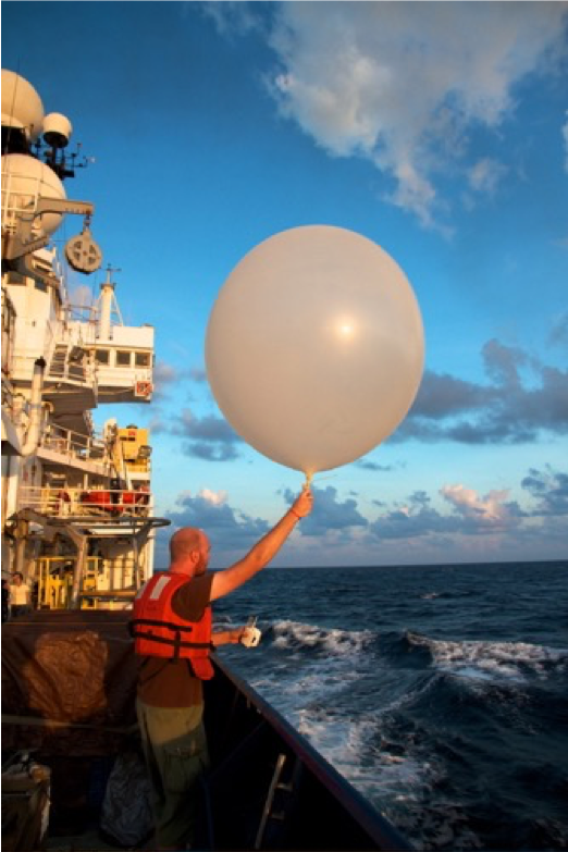 A researcher launches a radiosonde instrument attached to a weather balloon to capture detailed atmospheric data.