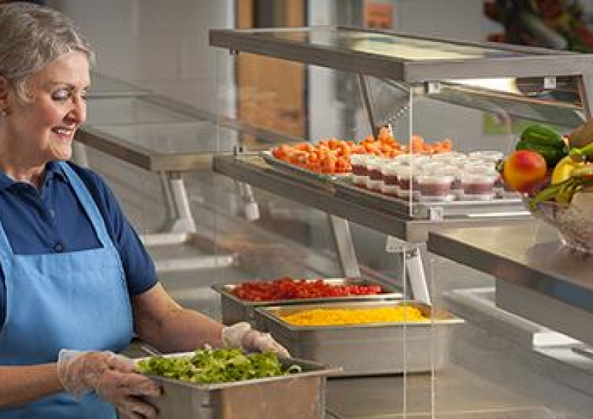 School Nutrition Professional prepares to serve meals behind counter