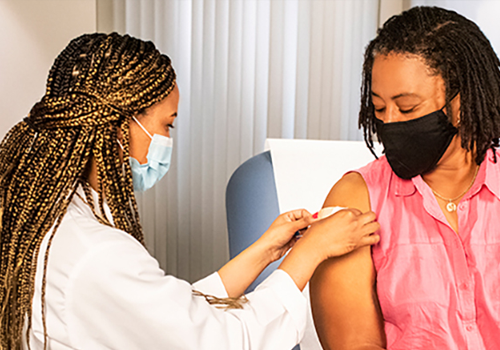 Una médica aplicando un apósito a una paciente después de vacunarla