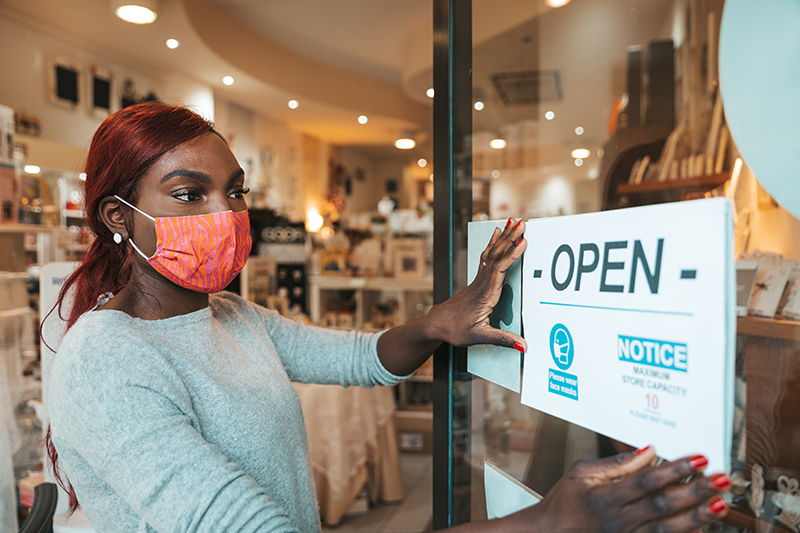 Worker in a mask posting a COVID-19 notice | Photo Credit: iStock-1282455397, LeoPatrizi