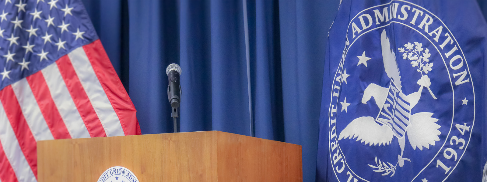 podium with US flag and NCUA seal flag behind