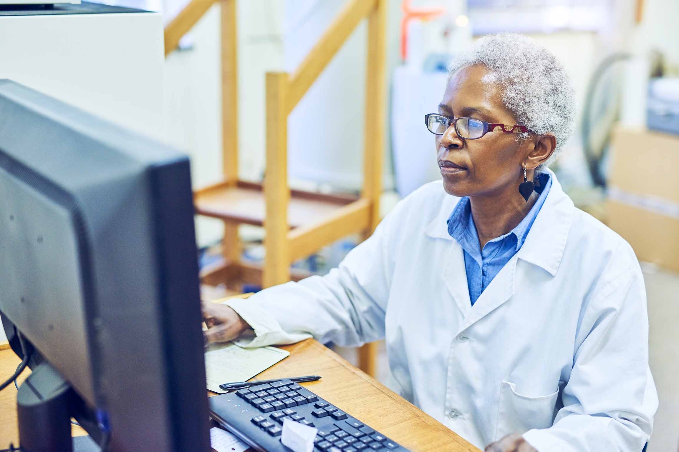 Older, African-American female scientist working at a desktop computer