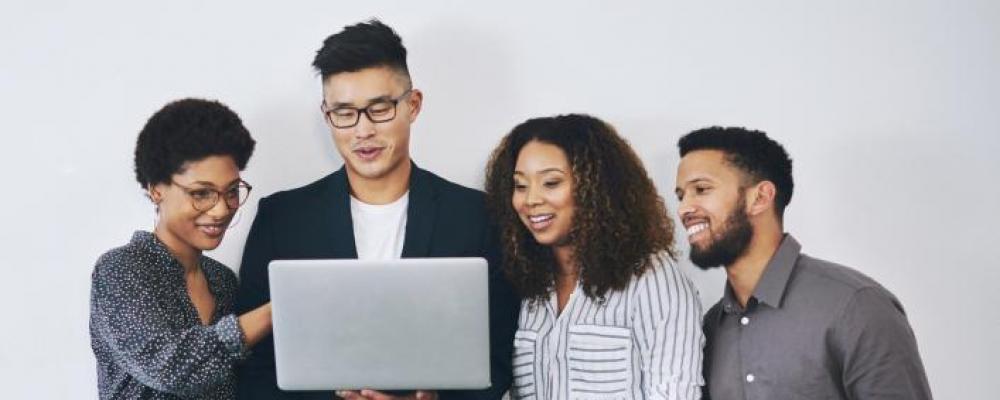 Group of four individuals looking at a laptop together