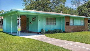 Blue-ish green one-story home with a prominent carport