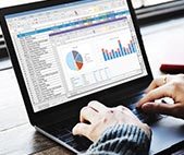 Woman using laptop while the screen displays graphs and spreadsheets