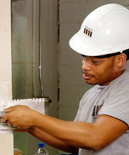 A Tile Setter spreads the mortar for a row of tiles.