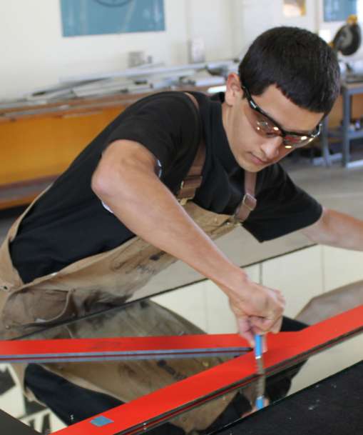 A glazier cuts a piece of glass.