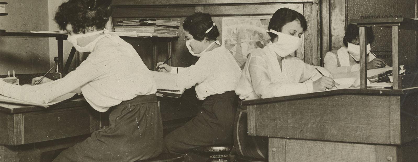 Girl clerks in New York at work with masks carefully tied about their faces.