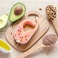 Photo of a salmon, avocado, grains, and olive oil