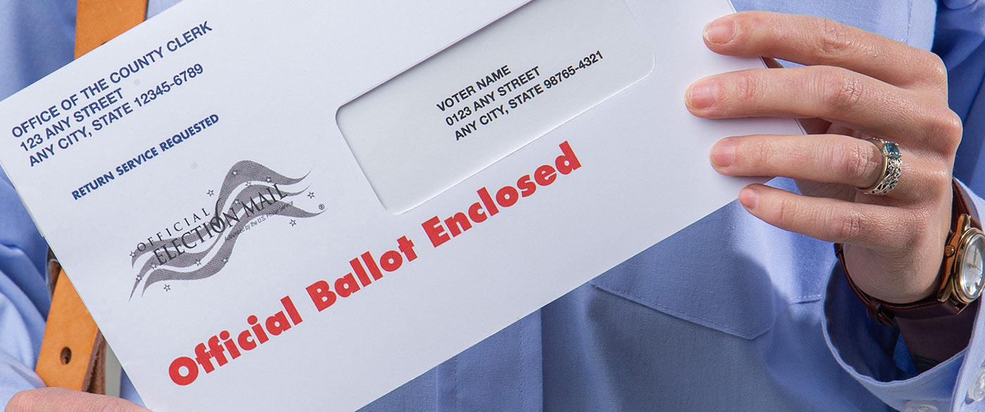 Postal carrier holding an official Election Mail ballot envelope.
