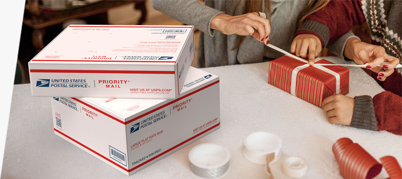 People wrapping holiday gifts they'll ship inside Priority Mail® boxes.