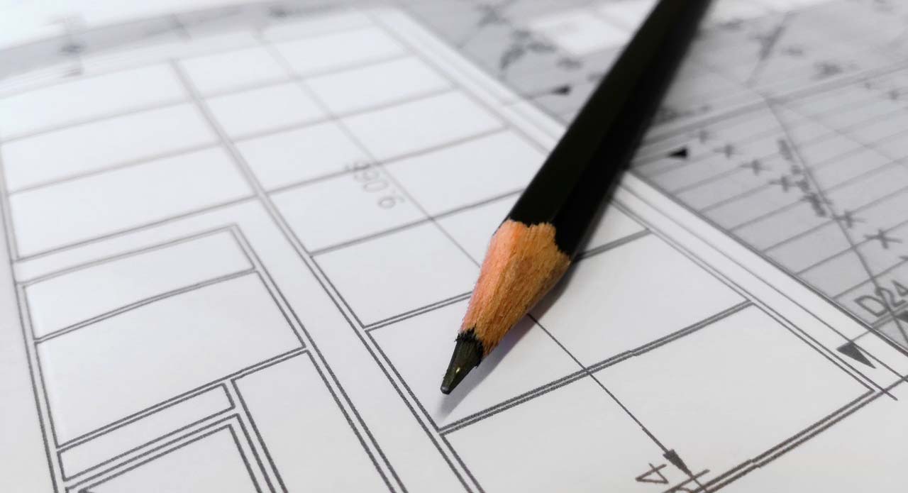 An image of a pencil lying on top of a blueprint page.