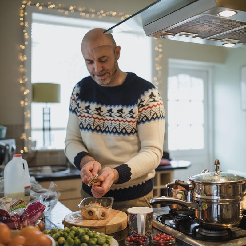 a man wearing a holiday sweater cooking a meal