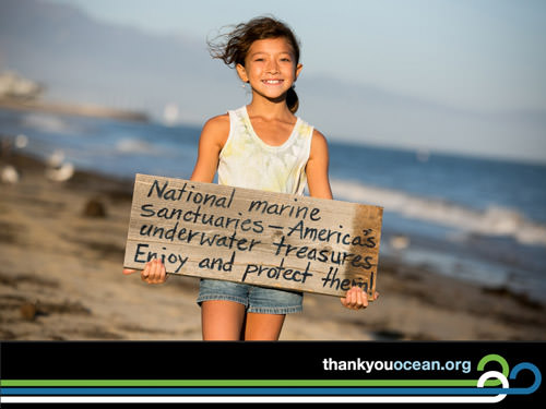 kid holding a sign saying: national marine sanctuaries - america's underwater treasures enjoy and protect them!