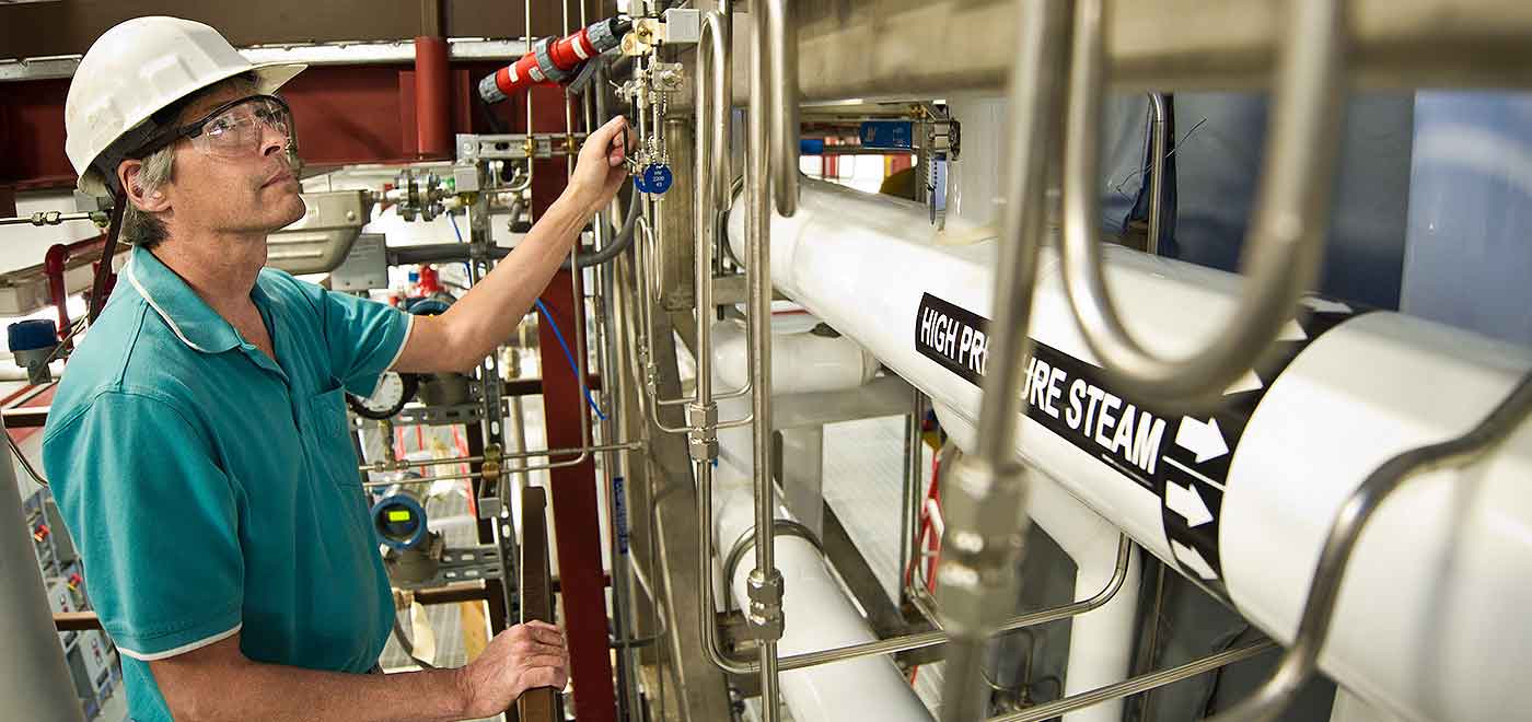 A man in a hard hat and safety glasses works on a pretreatment reactor.