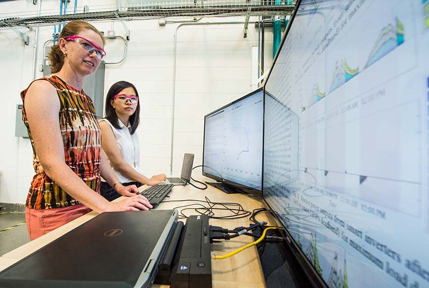 Two NREL partners in their lab at the Energy Systems Integration Facility.