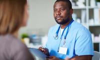 Doctor in scrubs talking to a patient and taking notes