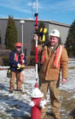 Municipal workers in hard hats using GPS equipment to record the location of a fire hydrant