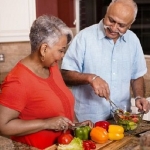 older woman and man cooking with vegetables