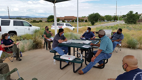 Representatives from the Santa Fe National Forest and the Pueblo of Jemez having a discussion at a picnic table under a shelter at the Santa Fe National Forest Supervisor's Office.