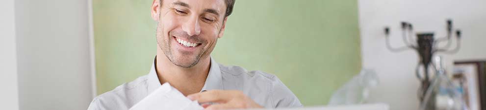 Small business owner opening customer reply mail envelopes.