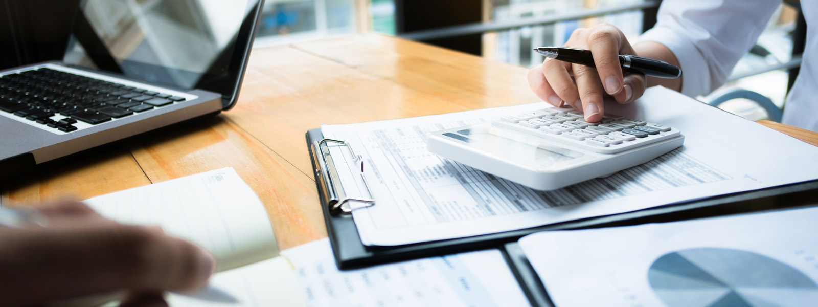 papers on a desk with people using a calculator and writing