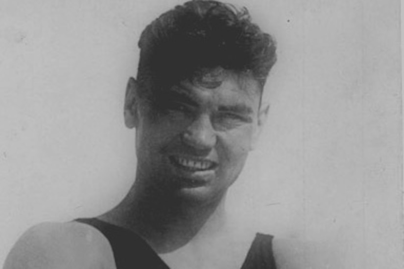 A man wearing a tank top has his arms crossed as he poses for a photo.