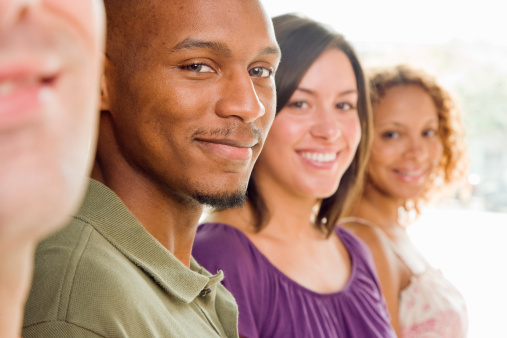 Four young men and women standing in a line and smiling