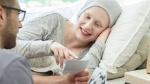 A hospice patient smiles and points at a photo held up to her by a man