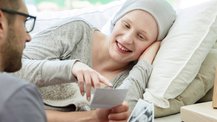 A hospice patient smiles and points at a photo held up by a man