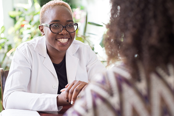 Young female doctor smiling at female patient in doctor's office.