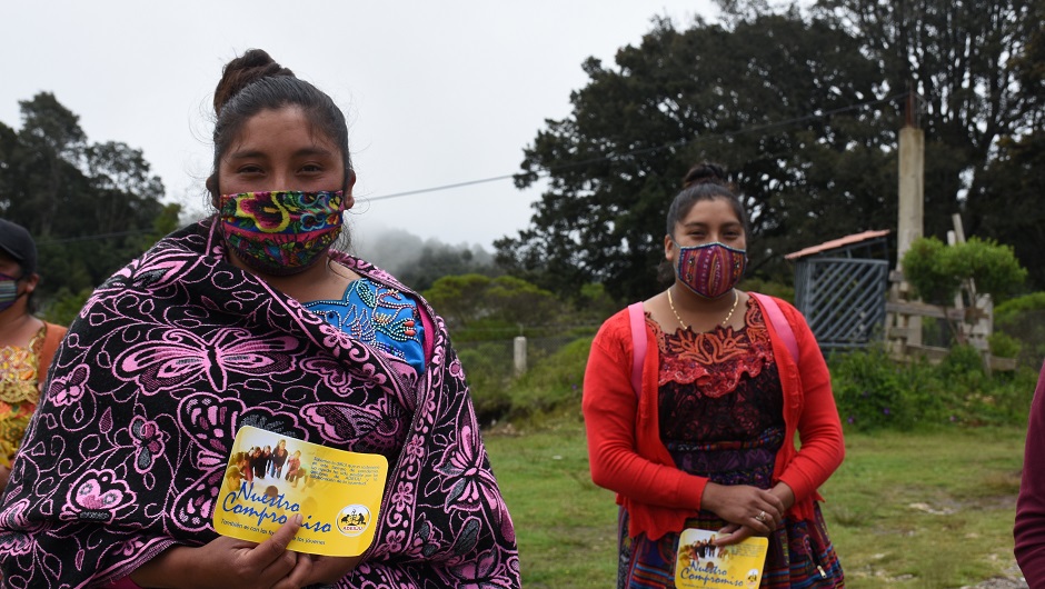 Two young Guatemalan women in masks stand with dignity.