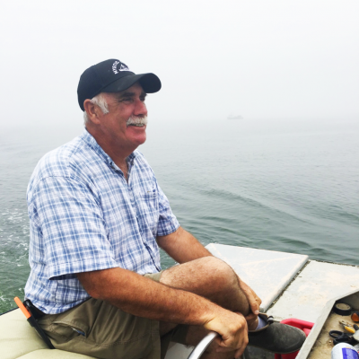 Jim Markow sits on a boat, preparing to work on the water on a foggy day.