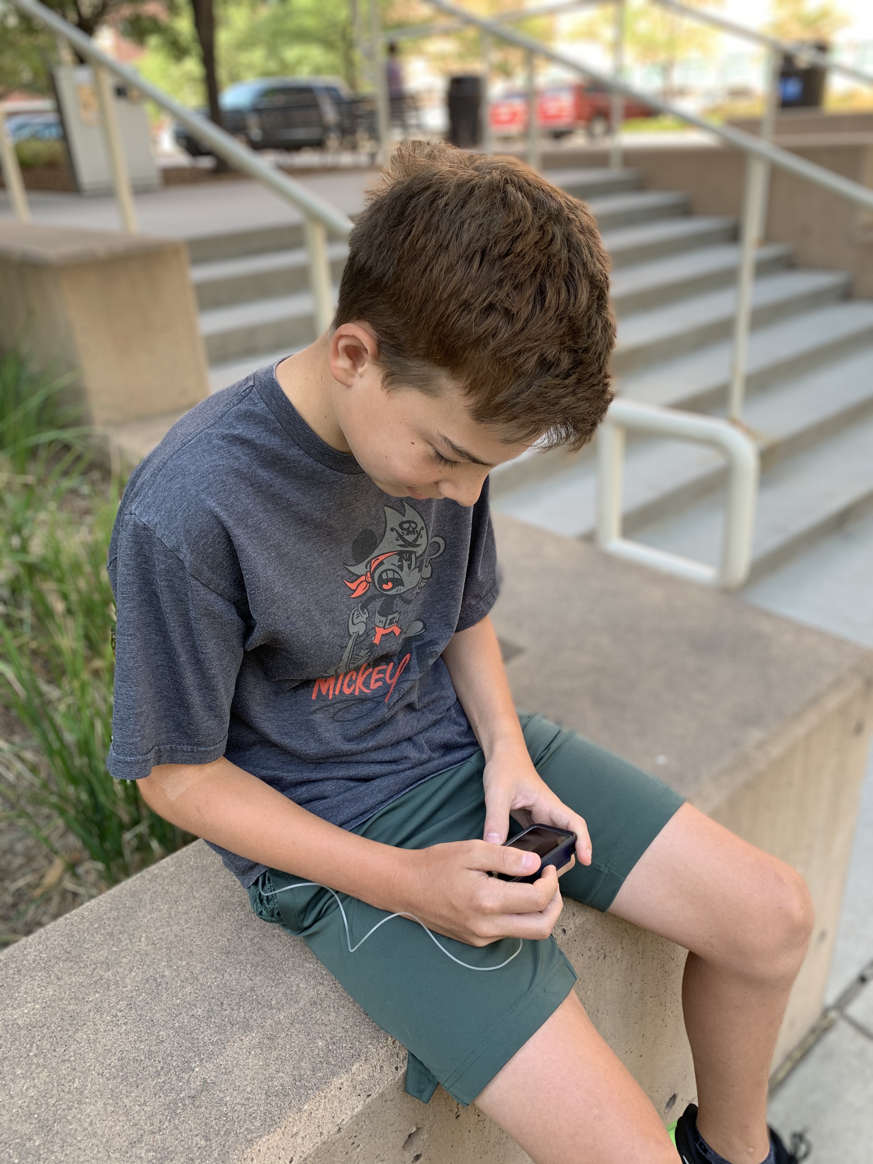 A child is sitting on a step reading data on his artificial pancreas device.