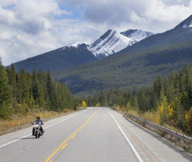 A motorbike is ridden with a mountainous backdrop.