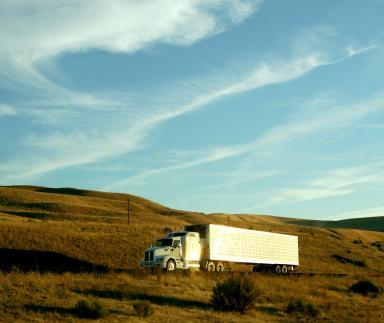 A truck driving by a hill.