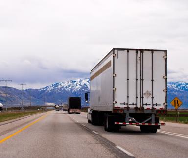 A white truck drives toward a mountain.