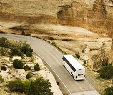 A motor-coach drives through a rocky landscape.